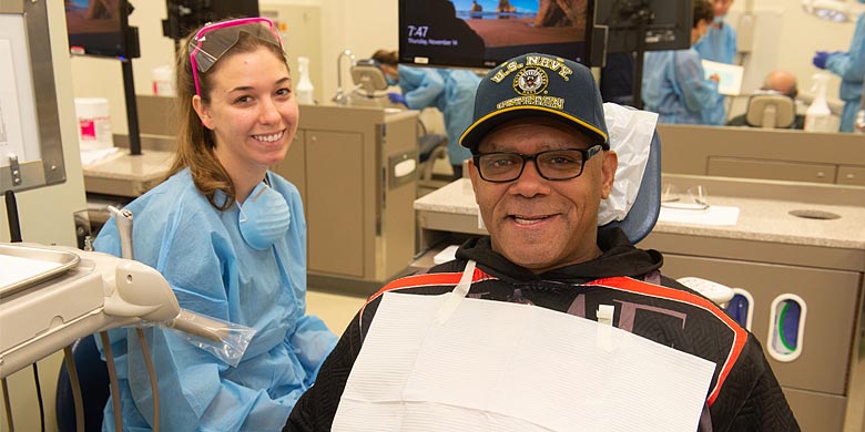 A female dental hygienist sits next to a male veteran